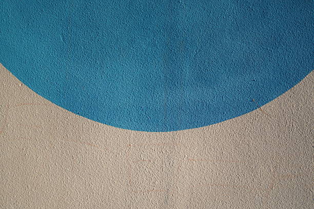 Abstract wall art featuring a smooth blue half-circle on a textured beige background, showcasing geometric form and color contrast.