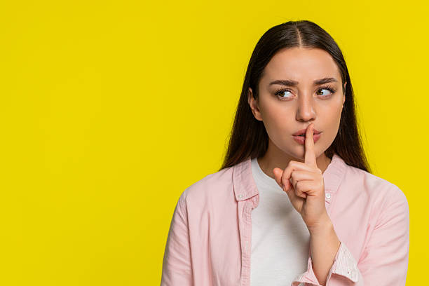 istock Woman placing finger on lips showing silence gesture asking for quiet serious thoughtful expression 2257360047