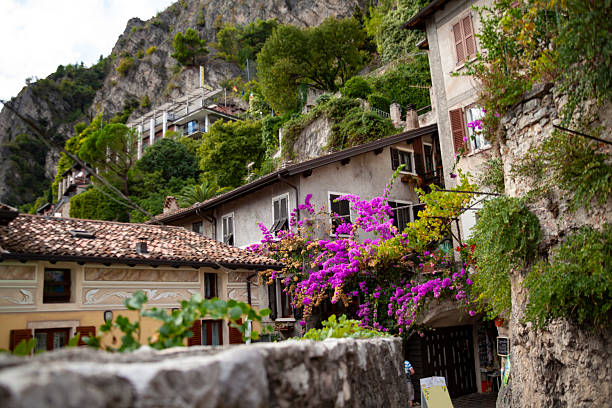 Set against the shimmering waters of Lake Garda, this photo captures the timeless charm of Limone sul Garda. Colorful houses with weathered facades and terracotta rooftops line the edge of the lake, their walls bearing the warm hues of ochre, yellow, and sun-faded red. Wooden posts rise from the water in the foreground, a reminder of the village’s long connection to fishing and boating.