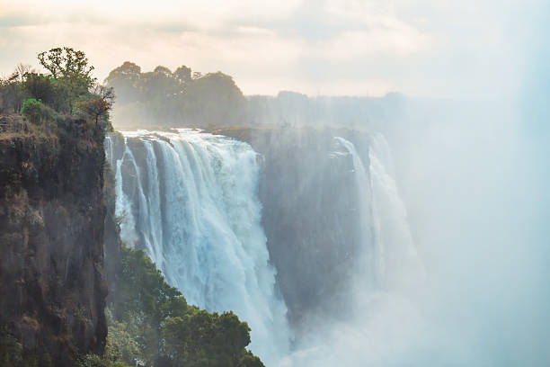 Victoria Falls, Matabeleland North, Zimbabwe: rainbow formed by the immense spray mist rising from Victoria Falls (known locally as Mosi-oa-Tunya, or \