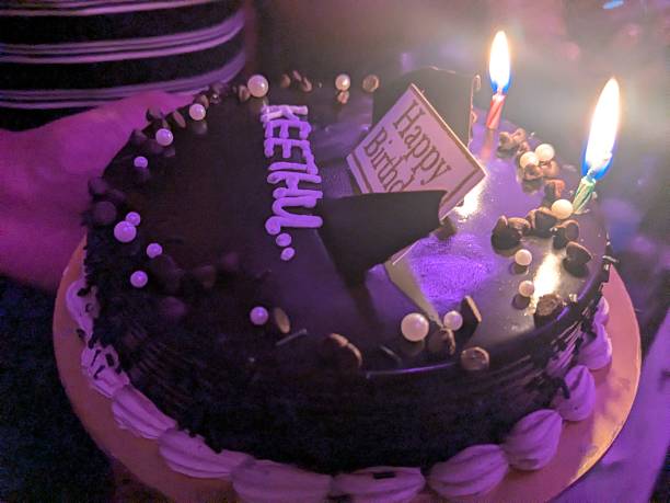 Close view of chocolate cake decorated with pearls and lit candles during celebration