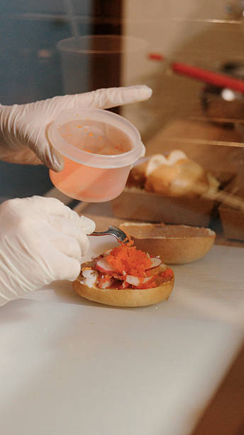 Close-up of hands preparing bagels, slicing and spreading cream cheese