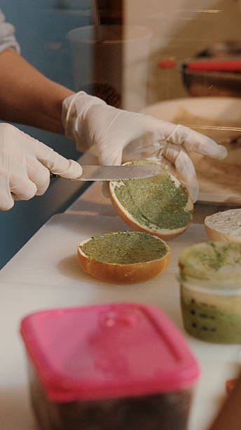 Close-up of hands preparing bagels, slicing and spreading cream cheese