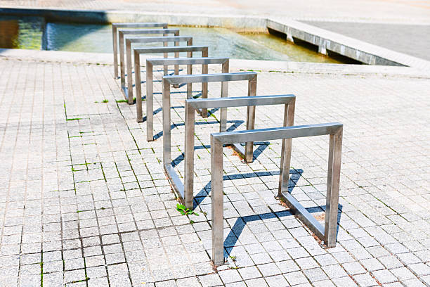 Modern metal bicycle racks stand empty on paved ground. Sleek, square U-shaped design awaits cyclists in the sunny public space