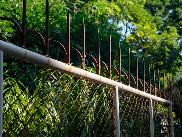 Weathered Chain Link Fence with Rusty Metal Security Spikes on Top