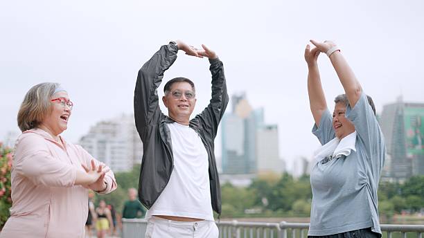 An elderly man and woman are jogging together in a park, chatting casually. This shared activity among retired seniors promotes good health, active aging, and awareness of long-term care, ensuring a stable and fulfilling retirement.