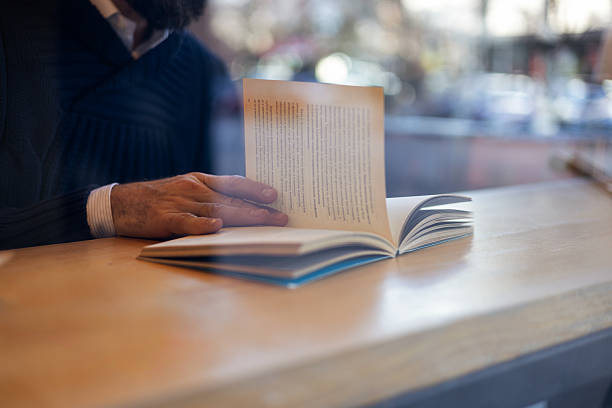 Close up image featuring a relaxed man reading literature in a cafe library. Concept of calm atmosphere, culture, and mental clarity.