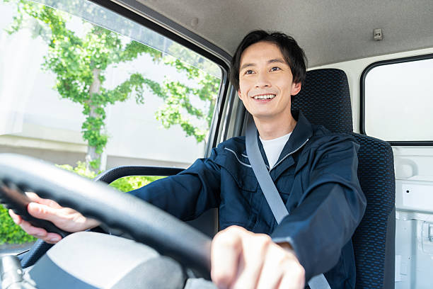 A young, Indian delivery person driving his van during a shift on a sunny day in Los Angeles, California.