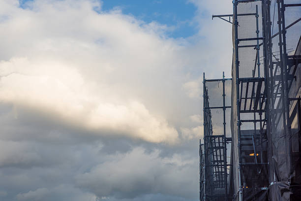 Apartment Building Under Renovation with Scaffolding Netting and Blue Sky (Copy Space)