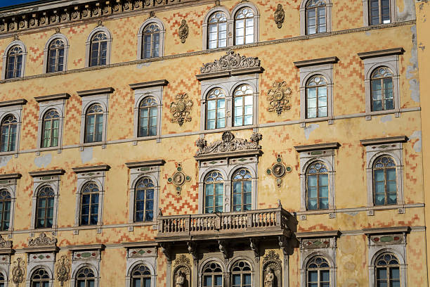 a richly decorated historic building facade featuring multiple arched windows, ornate stone carvings, and classical architectural elements. the warm yellow exterior is accented with painted patterns, sculptural details, and an elegant balcony. the intricate craftsmanship and symmetrical design highlight european heritage architecture and old‑world charm. ideal for themes of history, architecture, culture, and urban heritage.