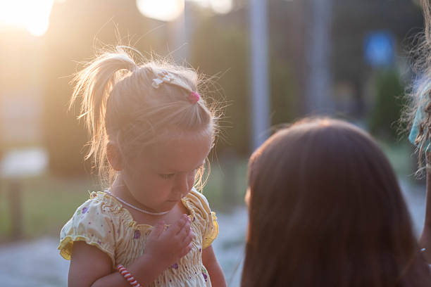Young child intently looking down in glowing golden hour light outdoors