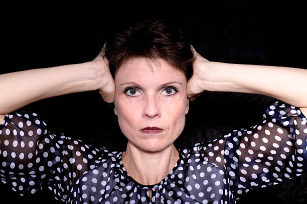 Expressive studio portrait of a woman looking directly at the camera against a black background.