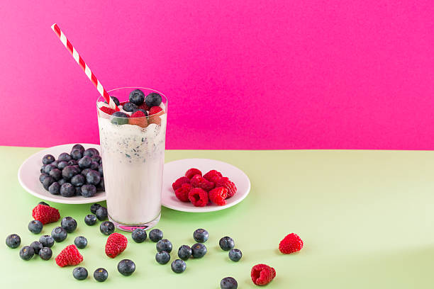 Colorful drink with berries on a green surface in a bright setting with pink background during daytime