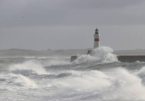 Fierce waves crashing against old lighthouse amid rough sea and strong winds