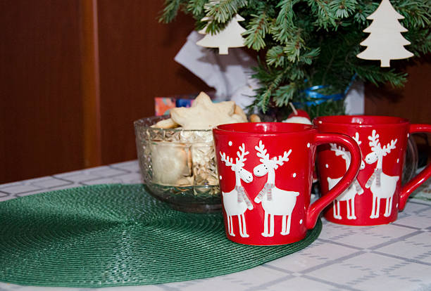A cup with hot drink on white table with advent wreath and red candles. Cozy festive home decor