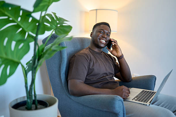 Young adult man working remotely and talking on smartphone