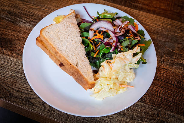Personal perspective - multiracial young woman eating a vegan lunch with friend.  Veggie hash and focaccia grilled vegetable panini with salad served at a diner in Vancouver, British Columbia, Canada.