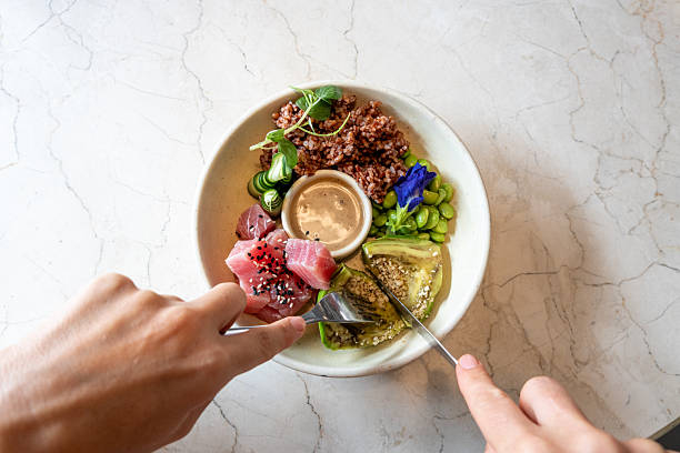 Hands cutting a food from a healthy plate full of food