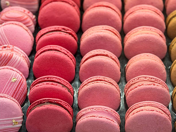 Stock photo shows a tempting assortment of pink and caramel macarons and macaroons from a bakery, featuring baked meringue-based cookies with creamy fillings and sweet textures. Perfect for dessert photography, pastry promotions, gourmet bakery displays