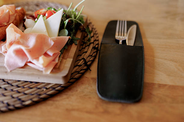 A freshly baked croissant filled with ham is served on a plate at a restaurant, presented as a delicious and appetizing breakfast or brunch option.