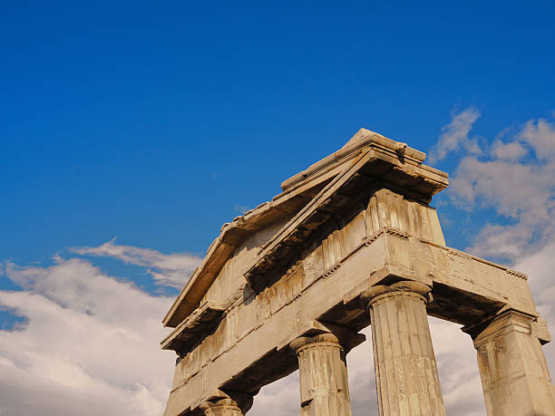Classical marble columns and architrave of ancient Greek temple ruins under dramatic blue sky