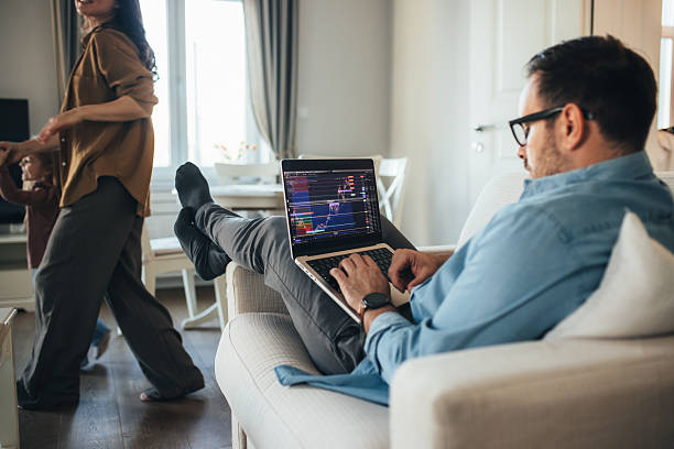 Young father and cryptocurrency trader working analyzing digital market charts and financial data at home