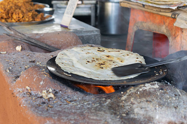 Traditional jowar and bajra flatbread roasting on a hot pan over a wood fire, showcasing rustic Maharashtrian cooking and authentic village flavors through slow roast and natural heat preparation.