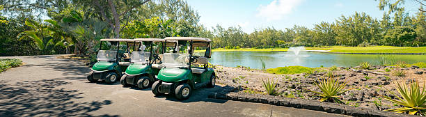 Golf cart drives around green course during day. Playing golf on a car