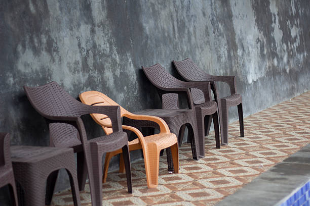 A group of modern blue plastic chairs with wooden legs arranged in neat rows on a tiled floor. The simple design and orderly layout create a minimalist and contemporary atmosphere. The image is ideal for illustrating meeting spaces, waiting rooms, or educational environments.