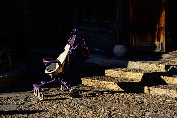 A purple stroller stands on an old cobblestone path, bathed in the warm golden light of sunset, creating a soft and nostalgic scene.