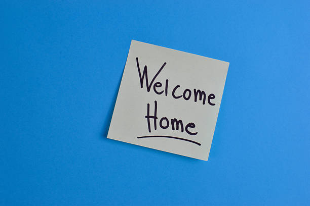 Yellow sticky note with Welcome Home message on blue background, conveying warmth and greeting through simple text and strong color contrast.