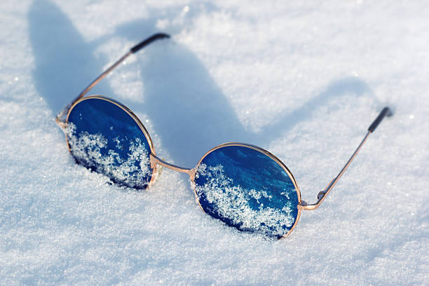 Cool hippie blue lens sunglasses on the bright white snow. The eye protection in winter season.