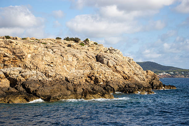 bare rocky high cliffs typical coast with cloudy sky in Ibiza, Spain