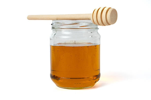 Simple glass jar filled with honey isolated on white. Clean food concept, organic product and minimal aesthetic.