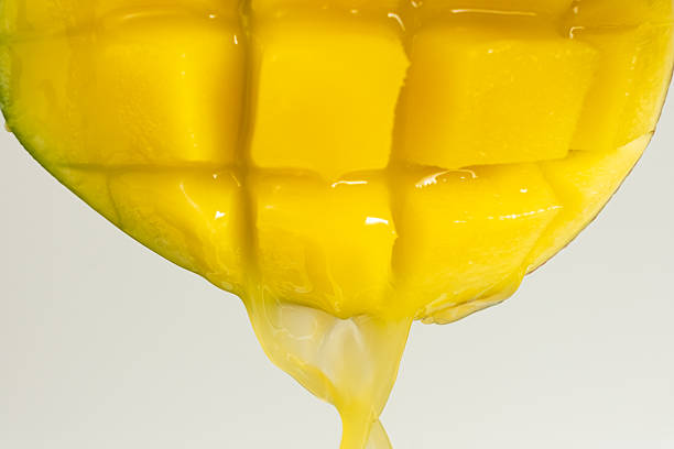 Macro of mango juice dripping from sliced fruit cubes.