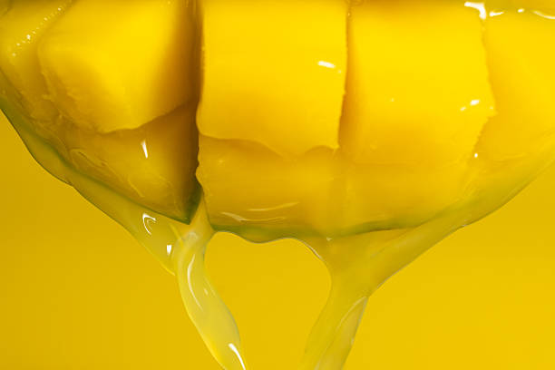 Macro of mango juice dripping from sliced fruit cubes.