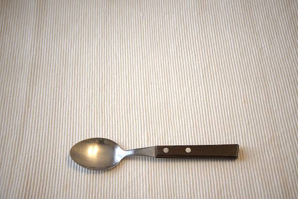 Single wooden handle spoon on a table with a clean white background, ample Copy Space, representing simplicity and minimalism in everyday life, suitable for cooking, home, and lifestyle imagery.