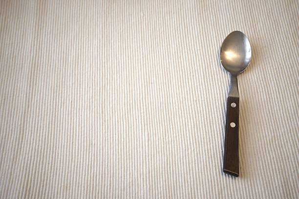 Single wooden handle spoon on a table with a clean white background, ample Copy Space, representing simplicity and minimalism in everyday life, suitable for cooking, home, and lifestyle imagery.