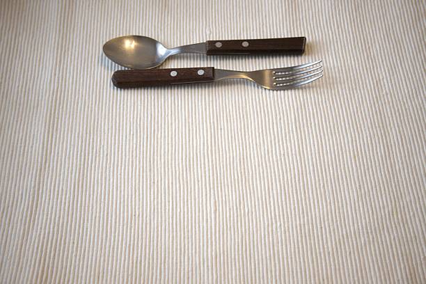 Wooden handle fork and spoon placed side by side on a table with clean white background, providing Copy Space, illustrating minimalism and simple lifestyle, ideal for culinary, home, and lifestyle projects.