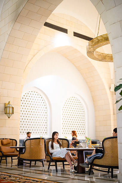 Five star hotel lobby lounge with arched stone architecture, a golden chandelier and guests seated in conversation