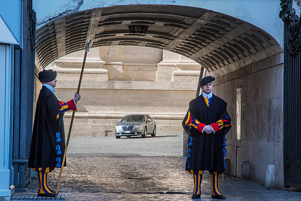 Vatican City, Vatican - May 28, 2023: Swiss Guard, in traditional uniform, stands at his post beneath an archway leading to Saint Peter's Square in Vatican City, holding a halberd