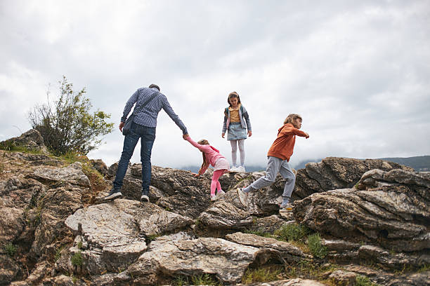 Father helps his teenage son while hiking on a sunny summer day. Family bonding, guidance, and support in nature, ideal for travel, lifestyle, and outdoor adventure concepts.
