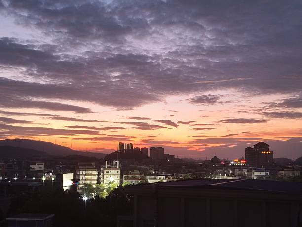 Sunset Over Cityscape with Dramatic Clouds and Silhouetted Buildings