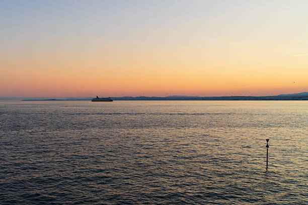 The sun's rays hit a boat sailing in the middle of the sea.