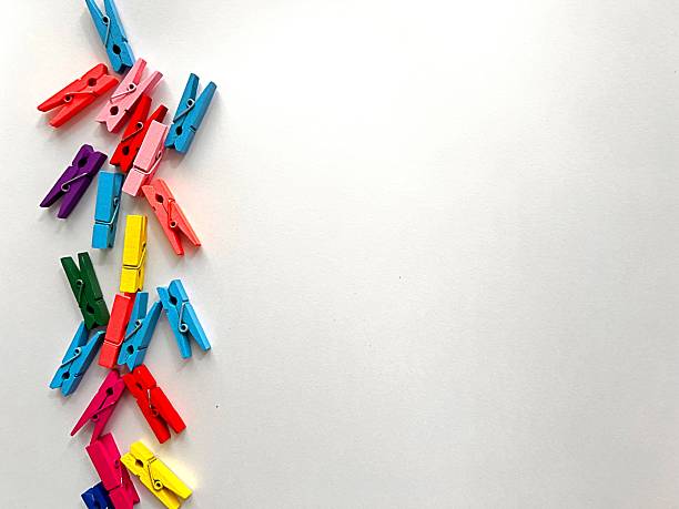 Red, yellow and wooden clothespins in a bowl on a stone underground, indoors.