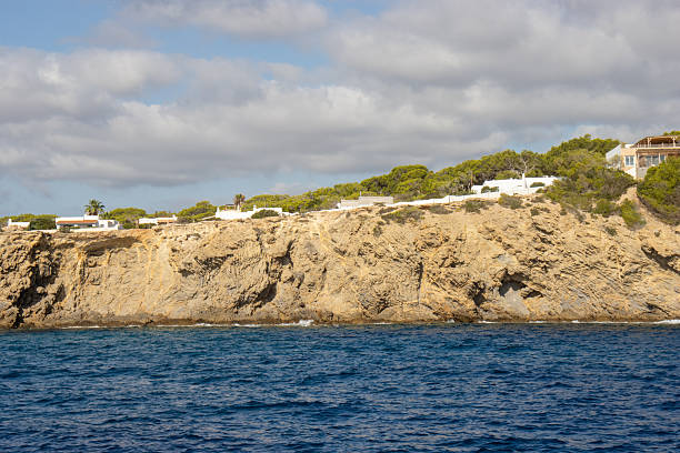 typical high cliffs with distant white buildings perched on the edge in Ibiza, Spain