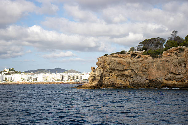 typical rock headland with cliff and trees with a cloudy sky in Ibiza, Spain