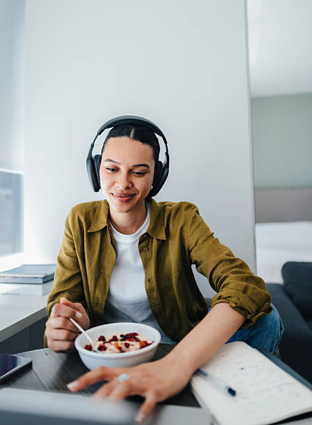 Casual Home Office Moment With Woman Wearing Headphones Enjoying Breakfast Bowl While Working
