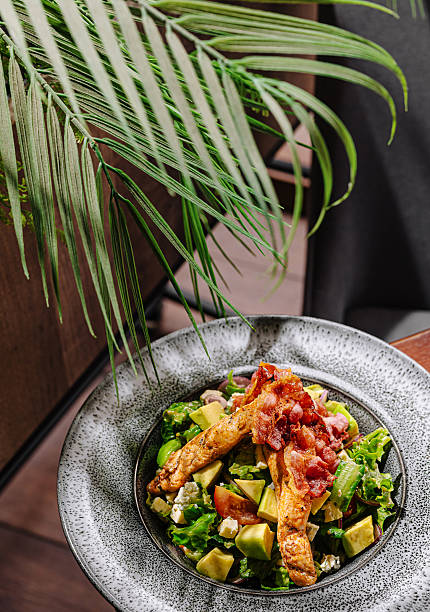 Fresh salad with grilled chicken and bacon served in a modern cafe setting