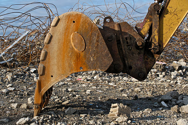 Rusty Excavator Bucket and Rebar on Construction Demolition Site. Close-up of Old Rusty Excavator Bucket with Exposed Rebar Against Blue Sky